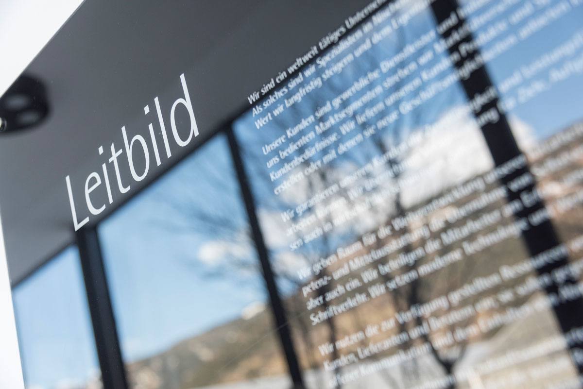 Blurry image of a sign with the word "Leitbild" in focus, against a defocused mountainous backdrop