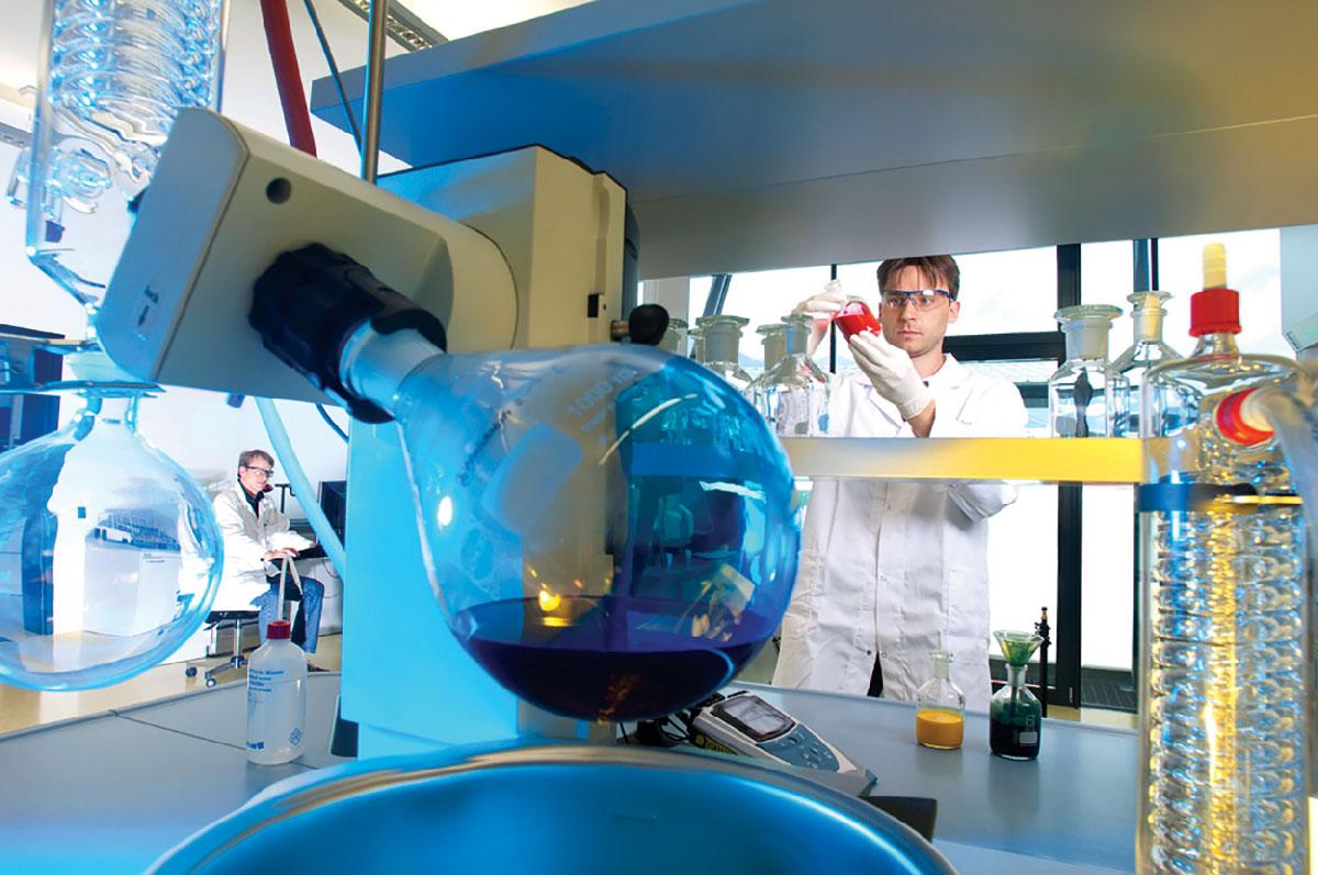 Scientist in lab coat working amid various glassware and lab equipment